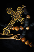 Load image into Gallery viewer, Close-up of a gold cross pendant with intricate designs on a dark background