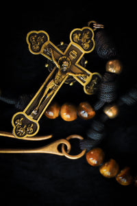 Close-up of a gold cross pendant with intricate designs on a dark background